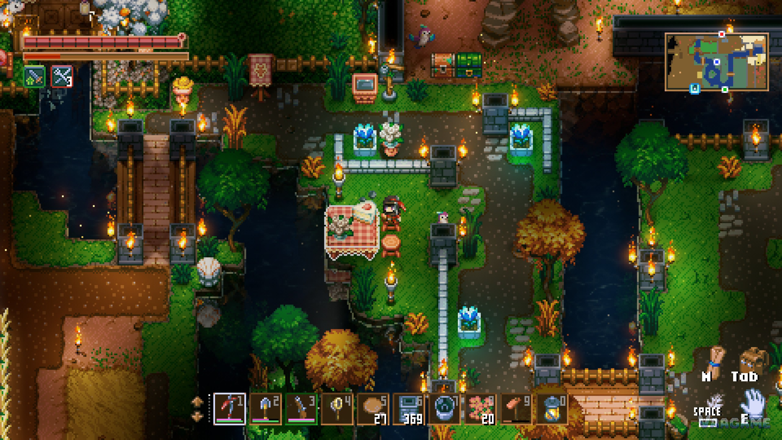 A waterside base interior with a picnic table, a stone bridge and flower beds