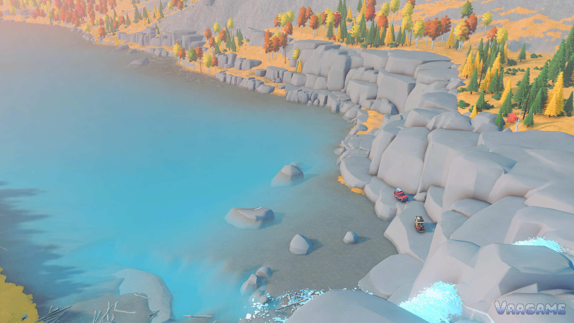 An aerial view of a turquoise lakeshore with two small vehicles on the rocks