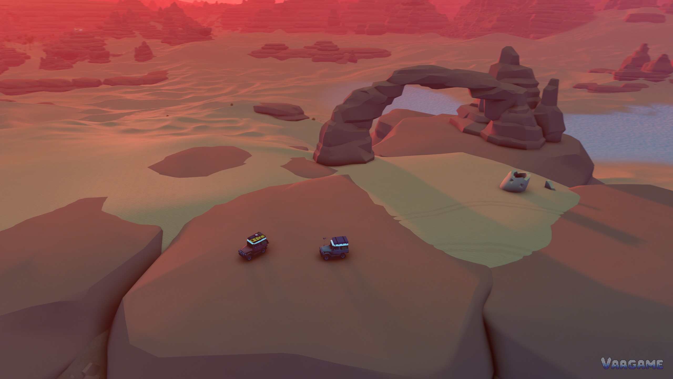 Two small trucks on a high red mesa plateau beside a natural rock arch