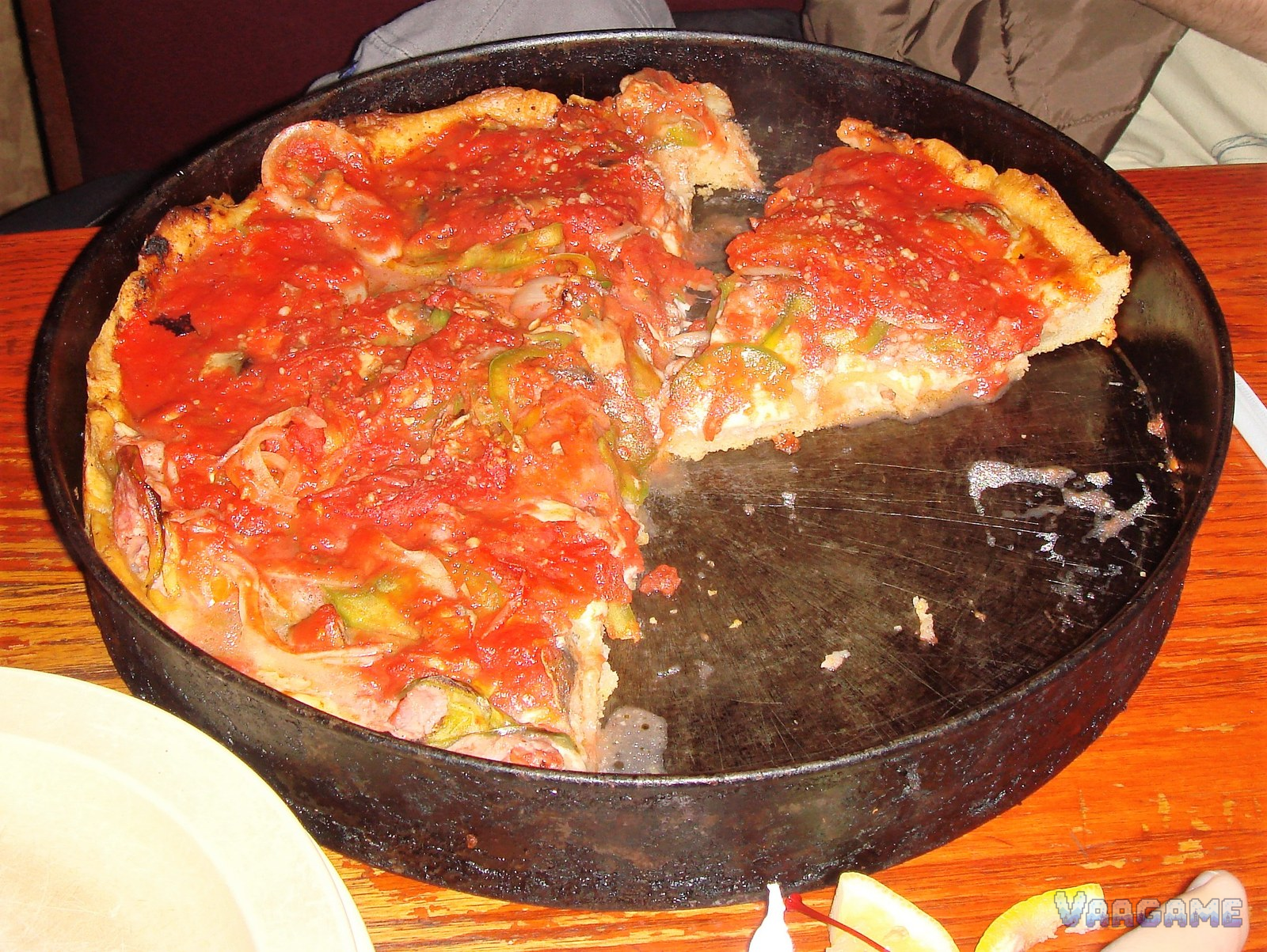 Chicago style deep dish pizza in a black pan with one slice removed